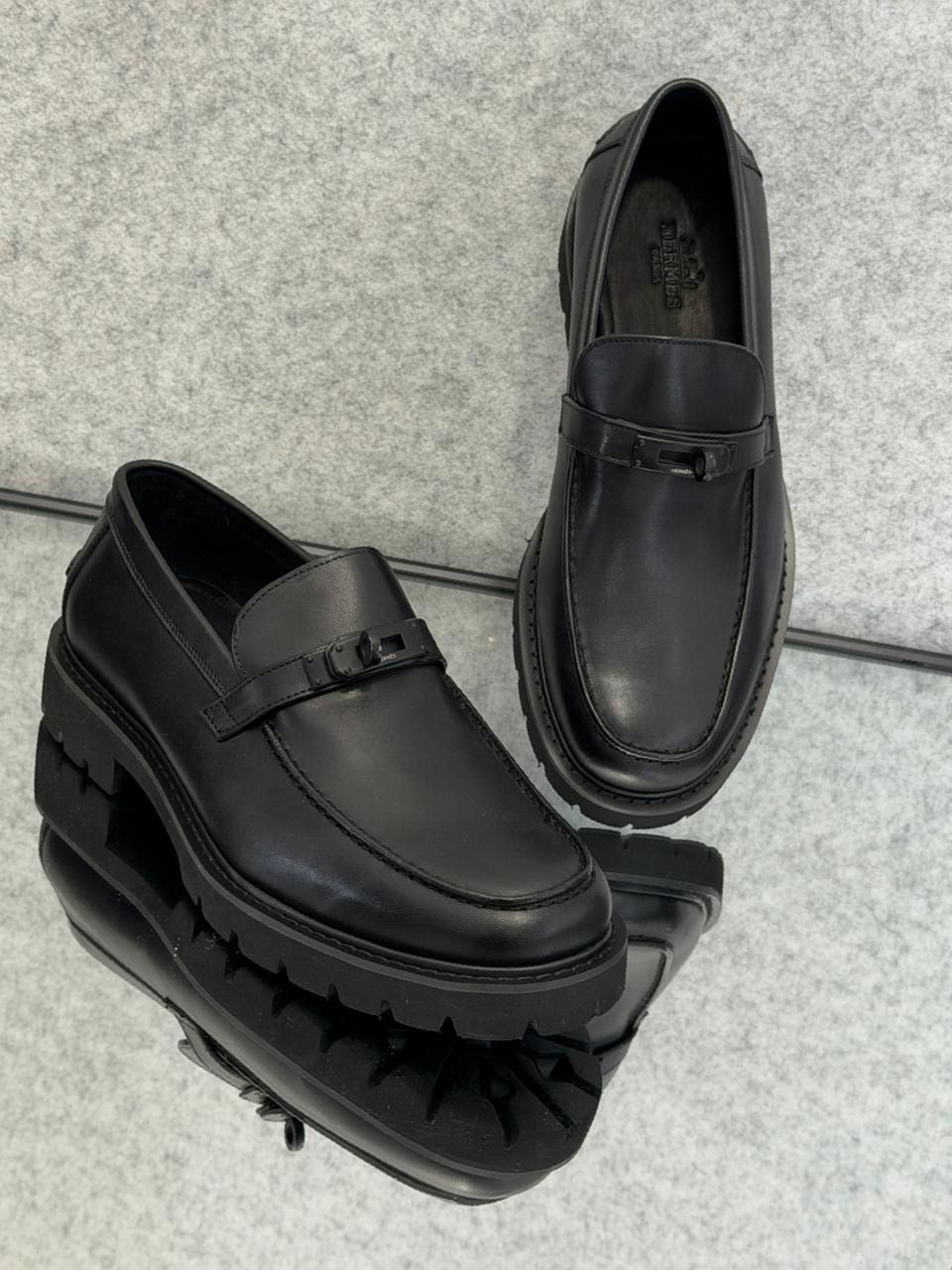 Hermès Icone loafer in black calfskin leather featuring a Kelly buckle and a light notched sole.