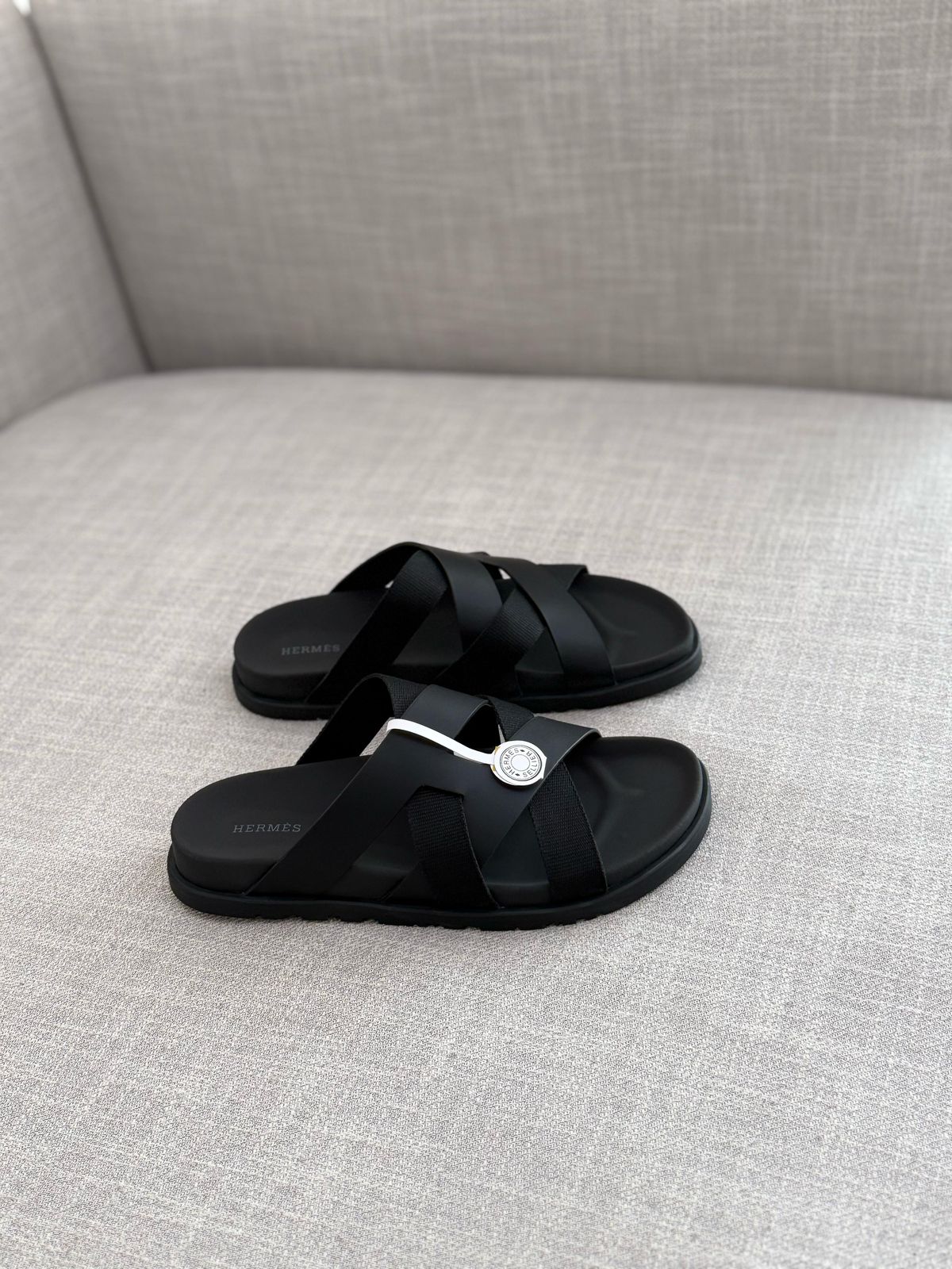 Hermès Kazimir sandal, crafted from black leather and fabric straps featuring an interlaced "H" silhouette.